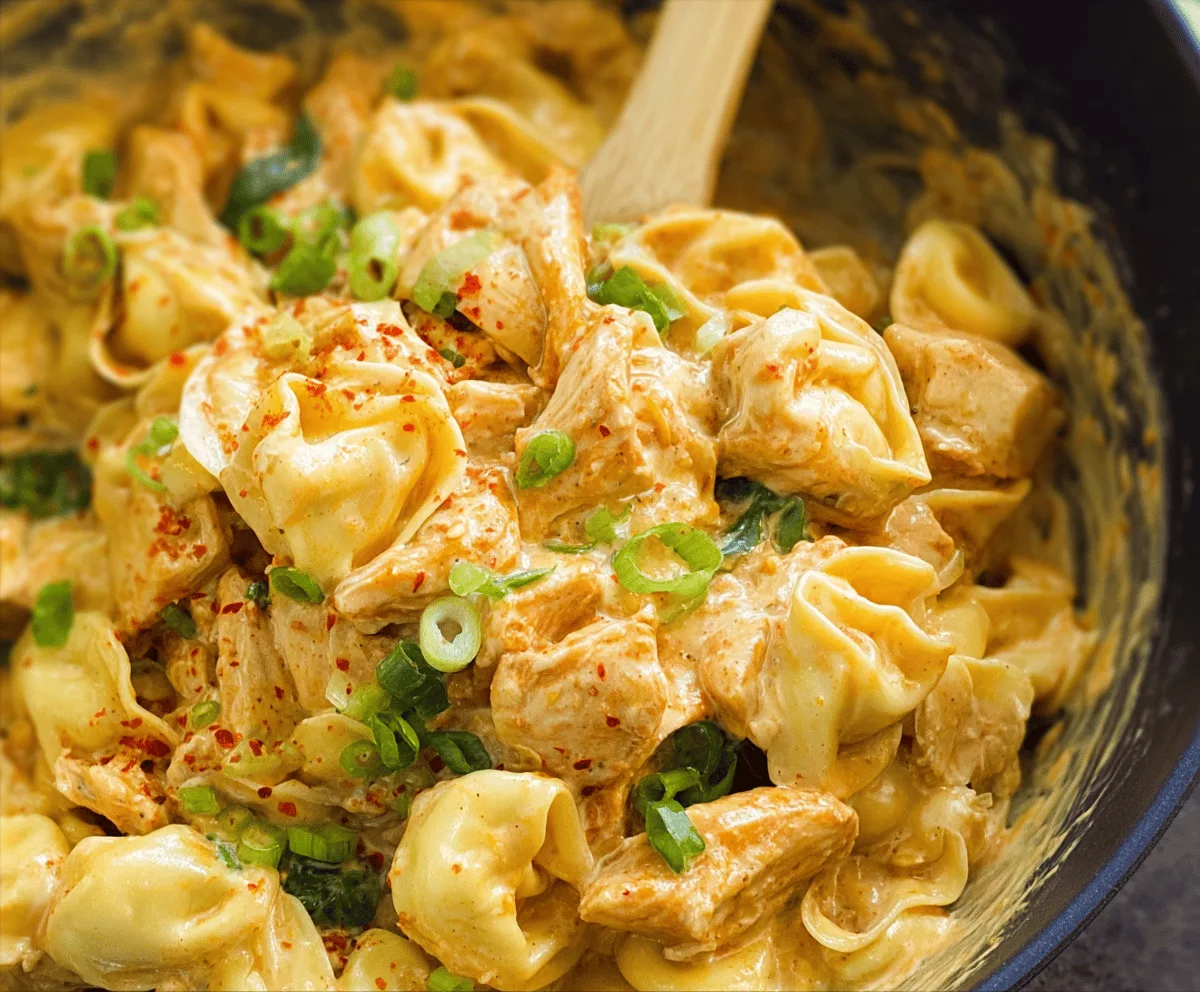 Creamy one-pot spicy garlic butter chicken tortellini dish with chicken, cheese tortellini, garlic, and spicy sauce in a skillet